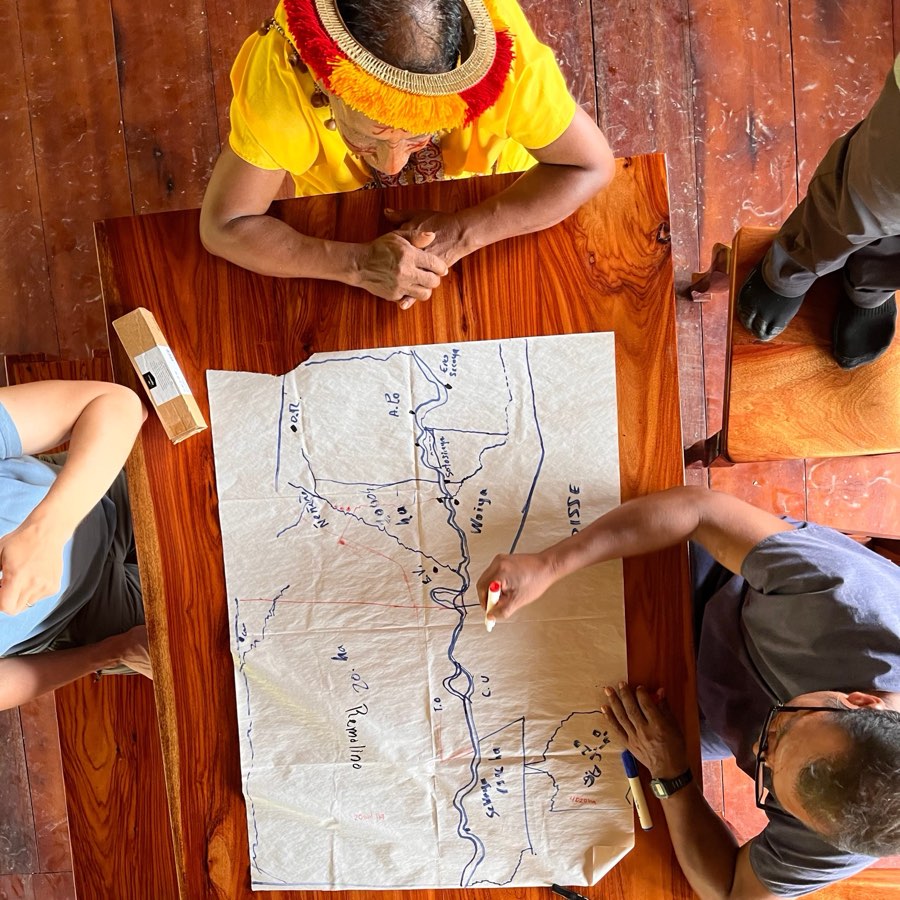 Overhead view of people working together on a hand-drawn map spread across a table
