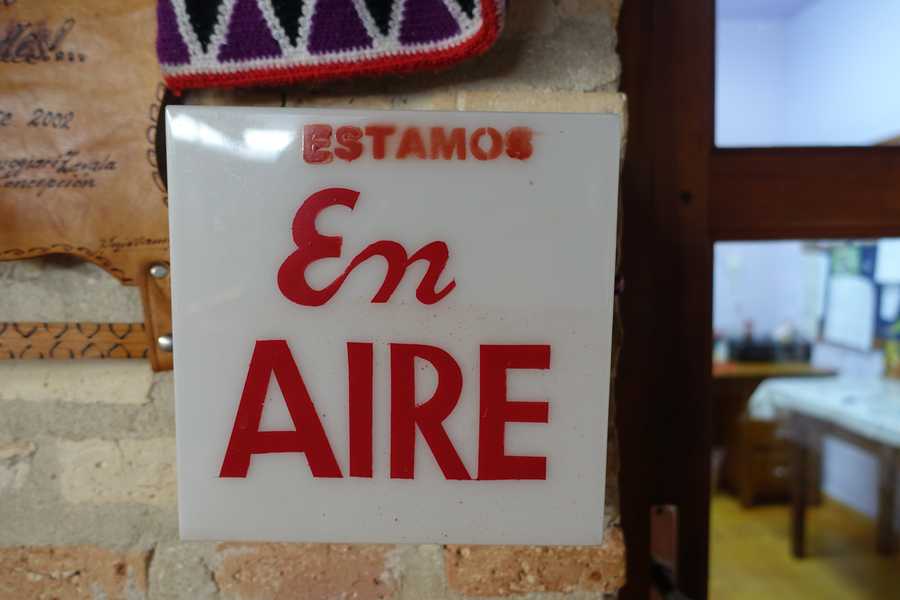 A sign reading “Estamos En Aire” — on the air — mounted on a brick wall.