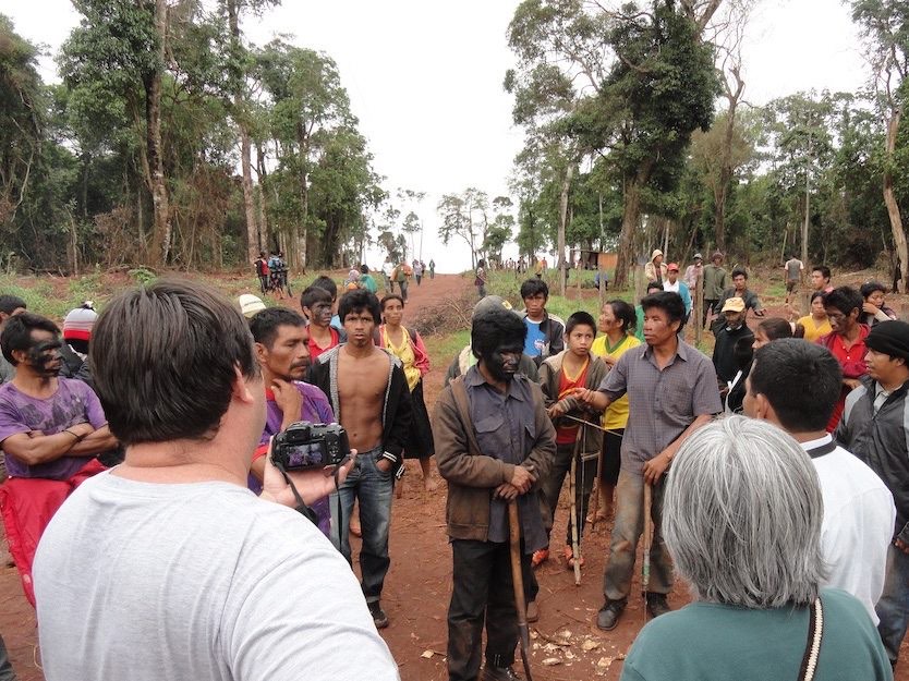 A large community assembly gathered on a forest road